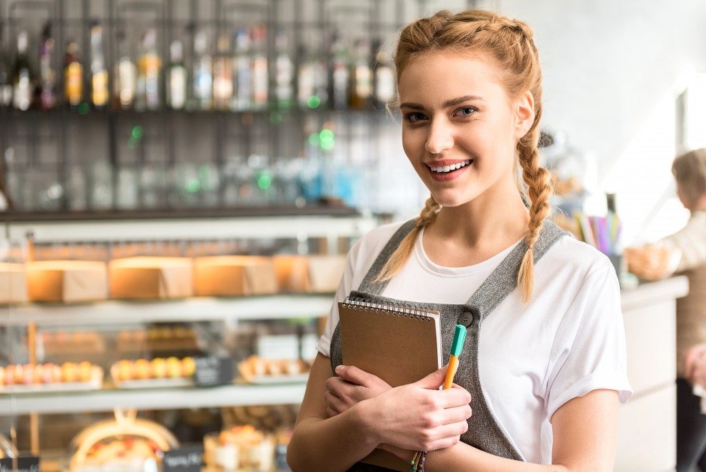 woman wearing a grey apron inside her bakery shop