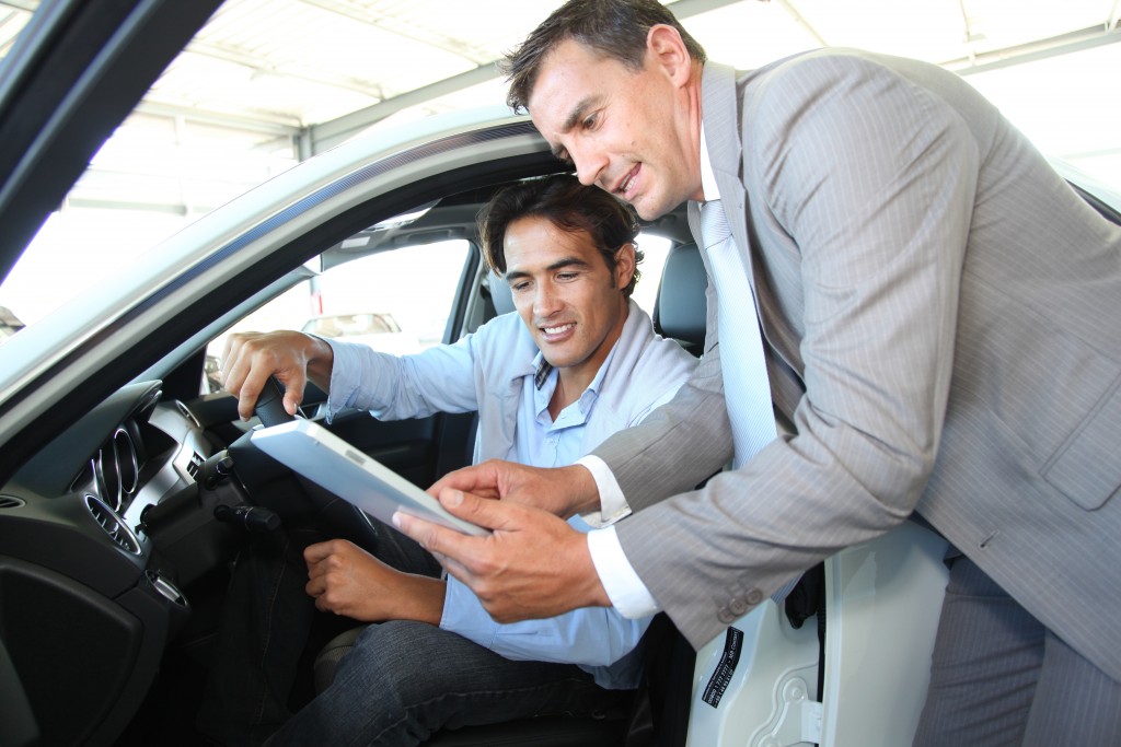 Car dealer with car buyer looking at tablet